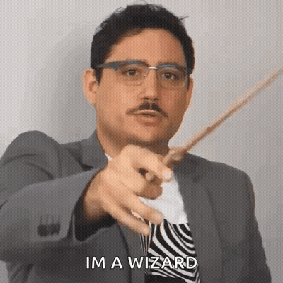 A Man In A Suit And Tie Is Pointing With A Wand And Saying `` Im A Wizard '' . GIF
