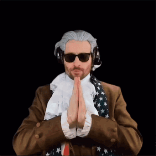 A Man In A Suit And Tie Is Praying In Front Of A Superhero GIF
