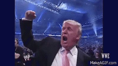 A Man In A Suit And Tie Is Raising His Fist In The Air GIF