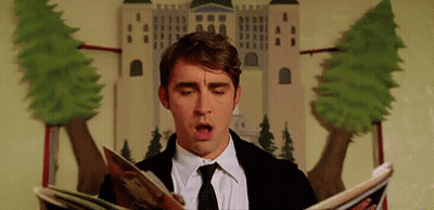 A Man In A Suit And Tie Is Reading A Magazine While Sitting In Front Of A Castle . GIF