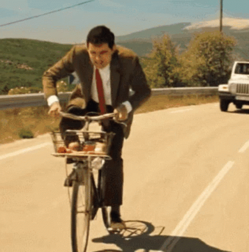 A Man In A Suit And Tie Is Riding A Bike GIF