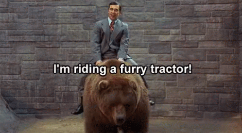 A Man In A Suit And Tie Is Riding A Furry Bear GIF
