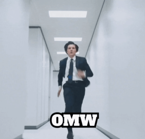 A Man In A Suit And Tie Is Running Down A Hallway With The Word Omw Written On The Bottom GIF