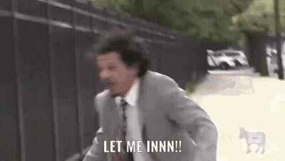 A Man In A Suit And Tie Is Running Down A Street And Saying `` Let Me Inn ! '' GIF