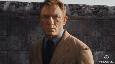 A Man In A Suit And Tie Is Running Down A Street With A Regal Logo In The Corner . GIF