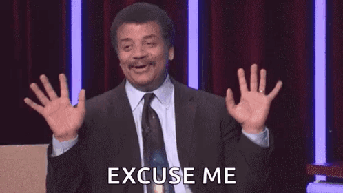 A Man In A Suit And Tie Is Saying Excuse Me With His Hands In The Air . GIF