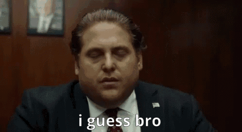 A Man In A Suit And Tie Is Saying `` I Guess Bro '' While Sitting At A Table . GIF