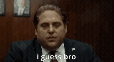 A Man In A Suit And Tie Is Saying `` I Guess Bro '' While Sitting In A Chair . GIF