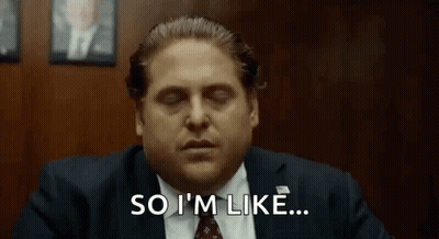 A Man In A Suit And Tie Is Saying `` So I 'M Like '' While Sitting At A Desk . GIF