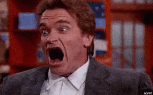 A Man In A Suit And Tie Is Screaming With His Mouth Wide Open . GIF