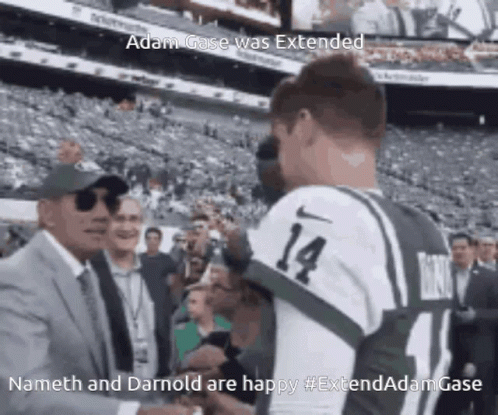 A Man In A Suit And Tie Is Shaking Hands With A Man In A Jersey With The Number 14 GIF