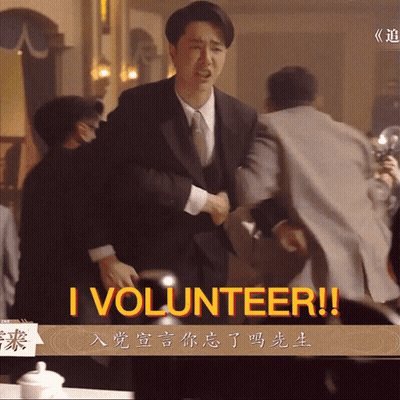 A Man In A Suit And Tie Is Shaking Hands With Another Man And The Words I Volunteer Are On The Screen GIF