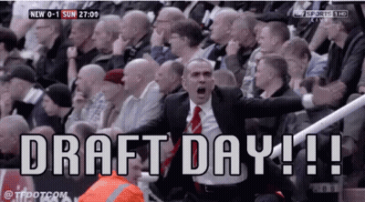 A Man In A Suit And Tie Is Shouting In Front Of A Crowd That Says Draft Day ! GIF