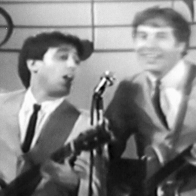 A Man In A Suit And Tie Is Singing Into A Microphone GIF