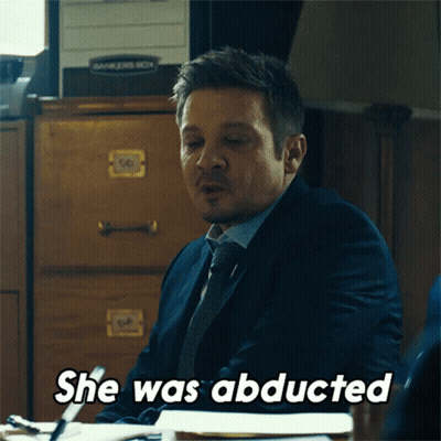 A Man In A Suit And Tie Is Sitting At A Desk And Says " She Was Abducted " GIF