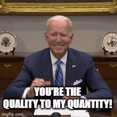 A Man In A Suit And Tie Is Sitting At A Desk And Smiling With The Words You 'Re The Quality To My Quantity . GIF