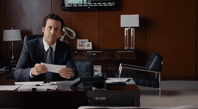 A Man In A Suit And Tie Is Sitting At A Desk Holding A Piece Of Paper With The Words So I Was Right Behind Him GIF