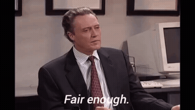 A Man In A Suit And Tie Is Sitting At A Desk In Front Of A Computer . GIF