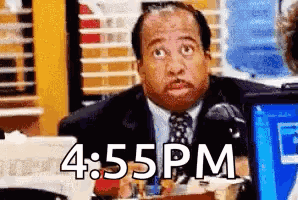 A Man In A Suit And Tie Is Sitting At A Desk With 4:55 Pm Written On The Bottom . GIF