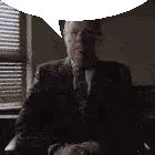 A Man In A Suit And Tie Is Sitting At A Desk With A Speech Bubble Above His Head . Sticker