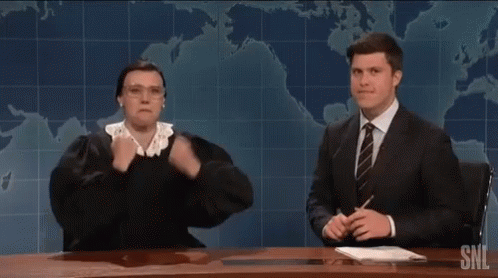 A Man In A Suit And Tie Is Sitting At A Desk With A Woman In A Judge 'S Outfit . GIF