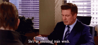 A Man In A Suit And Tie Is Sitting At A Desk With A Woman . GIF