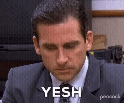 A Man In A Suit And Tie Is Sitting At A Desk With His Eyes Closed And Says Yesh . GIF