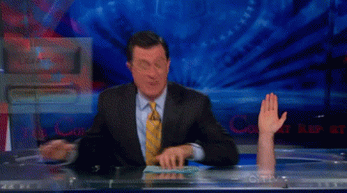 A Man In A Suit And Tie Is Sitting At A Desk With His Hand Up In Front Of A Screen That Says Cnn GIF