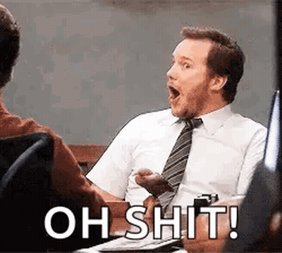 A Man In A Suit And Tie Is Sitting At A Desk With His Mouth Open And The Words `` Oh Shit ! '' GIF