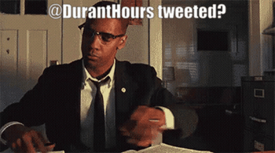 A Man In A Suit And Tie Is Sitting At A Desk With The Words " Duranthours Tweeted " Written Above Him GIF