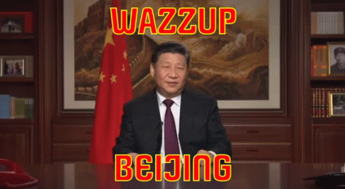 A Man In A Suit And Tie Is Sitting At A Desk With The Words Wazzup Beijing Above Him GIF
