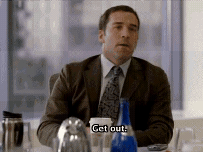 A Man In A Suit And Tie Is Sitting At A Table And Talking . GIF