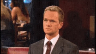 A Man In A Suit And Tie Is Sitting At A Table GIF