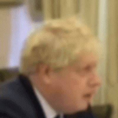 A Man In A Suit And Tie Is Sitting At A Table . GIF