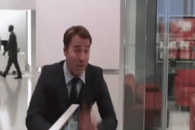 A Man In A Suit And Tie Is Sitting At A Table In A Room With A Glass Wall . GIF