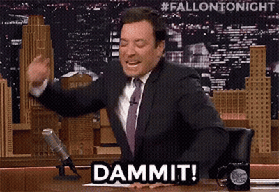 A Man In A Suit And Tie Is Sitting At A Table In Front Of A Microphone And Says Dammit . GIF
