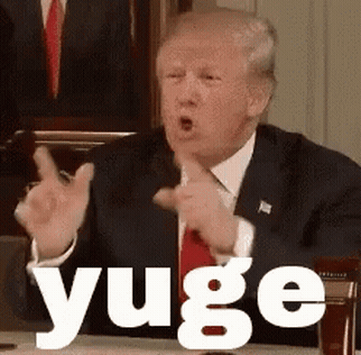 A Man In A Suit And Tie Is Sitting At A Table Making A Funny Face And Says Yuge . GIF