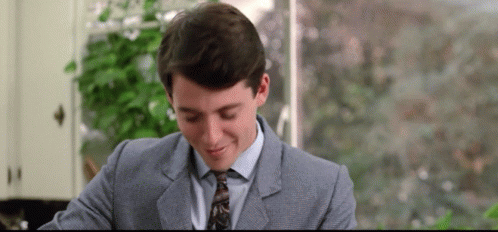 A Man In A Suit And Tie Is Sitting At A Table . GIF