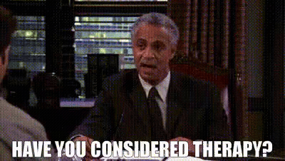 A Man In A Suit And Tie Is Sitting At A Table Talking To Another Man And Asking If He Considers Therapy . GIF