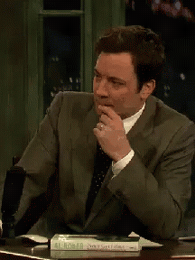 A Man In A Suit And Tie Is Sitting At A Table With A Book On It That Says Al Robert GIF