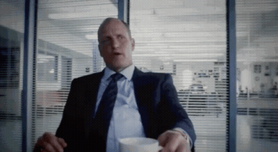 A Man In A Suit And Tie Is Sitting At A Table With A Cup Of Coffee . GIF