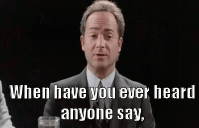 A Man In A Suit And Tie Is Sitting At A Table With A Glass Of Water And A Quote . GIF