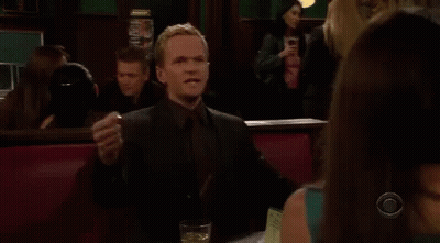 A Man In A Suit And Tie Is Sitting At A Table With A Glass Of Wine . GIF
