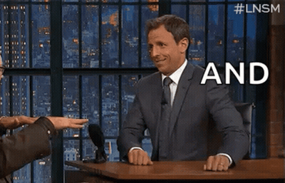 A Man In A Suit And Tie Is Sitting At A Table With A Microphone And Talking To Another Man . GIF
