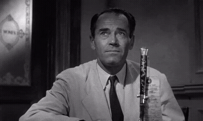 A Man In A Suit And Tie Is Sitting At A Table With A Microphone In Front Of Him GIF