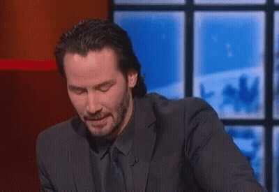 A Man In A Suit And Tie Is Sitting At A Table With His Eyes Closed . GIF