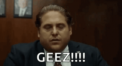 A Man In A Suit And Tie Is Sitting At A Table With His Eyes Closed And Says Geez !!! GIF