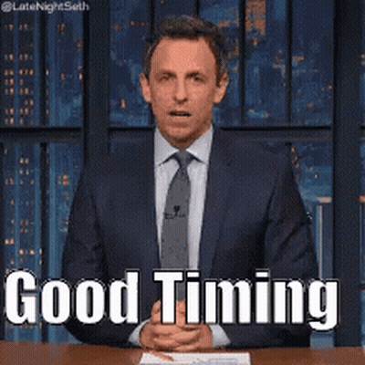 A Man In A Suit And Tie Is Sitting At A Table With His Hands Folded And Says Good Timing . GIF