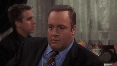 A Man In A Suit And Tie Is Sitting At A Table With Other Men GIF