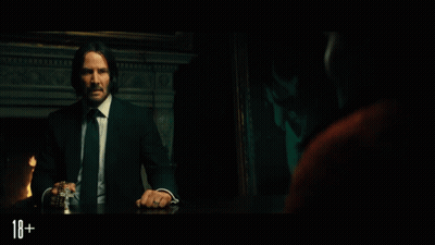 A Man In A Suit And Tie Is Sitting At A Table With The Number 18 On The Bottom Right GIF